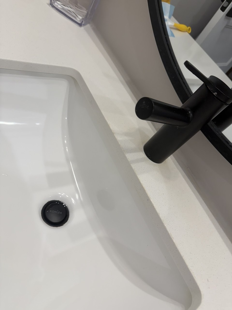 The same black tap and basin after cleaning, with a clean white countertop and a bright, spotless sink
