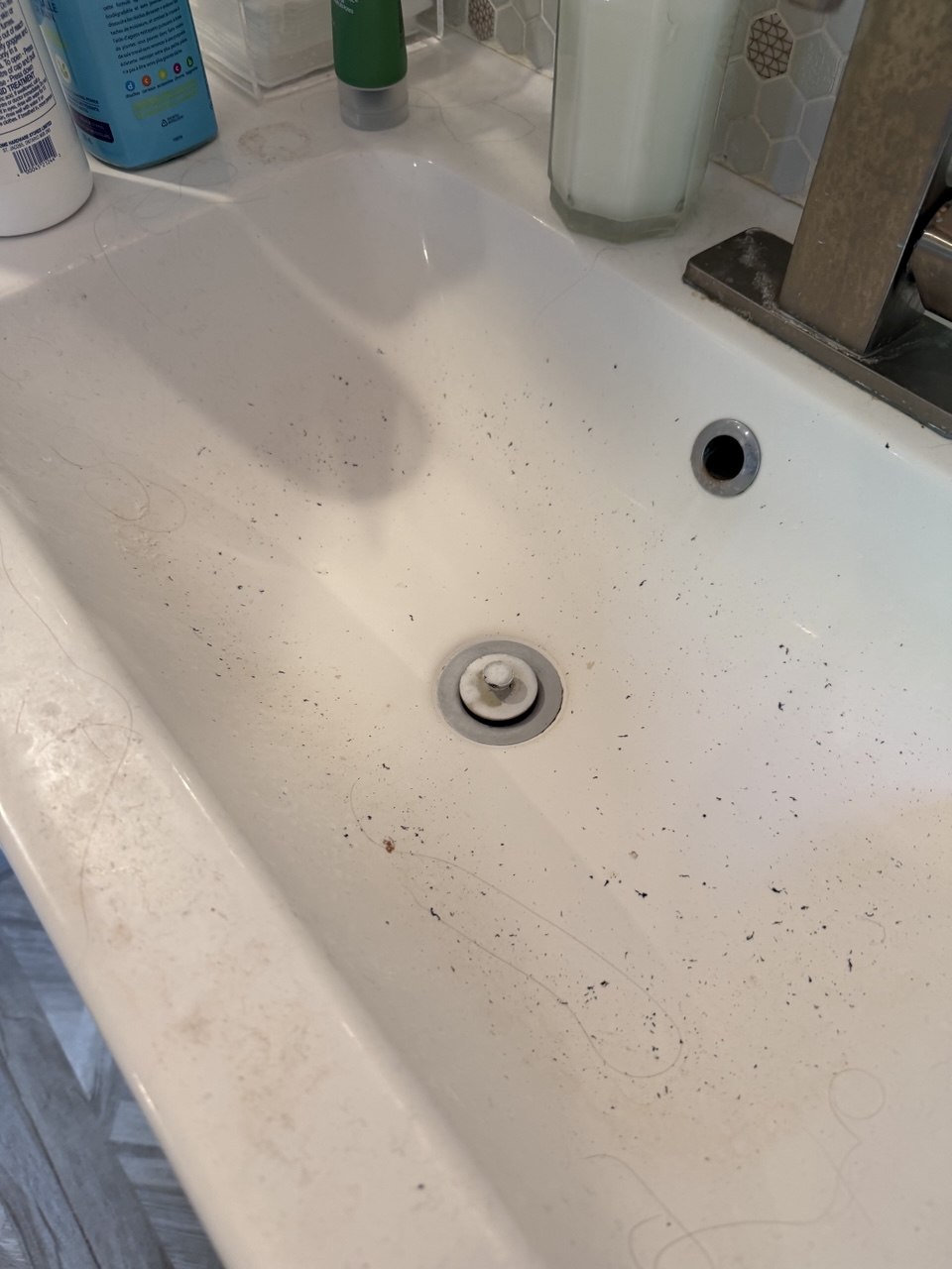 Bathroom sink before cleaning, with hair and grime scattered around the drain