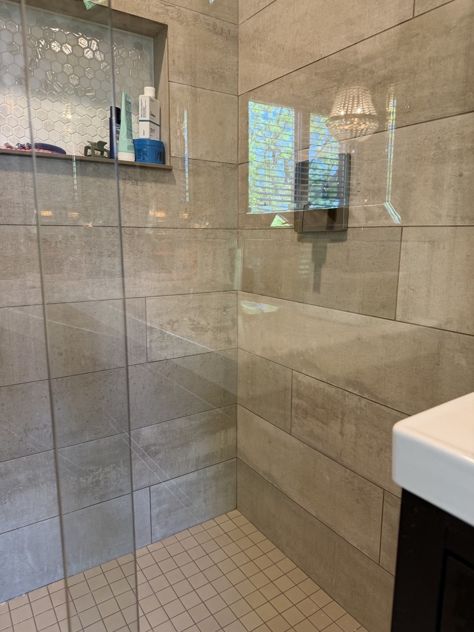 The same shower enclosure after cleaning, with streak-free glass and clear views of the tiled walls behind it
